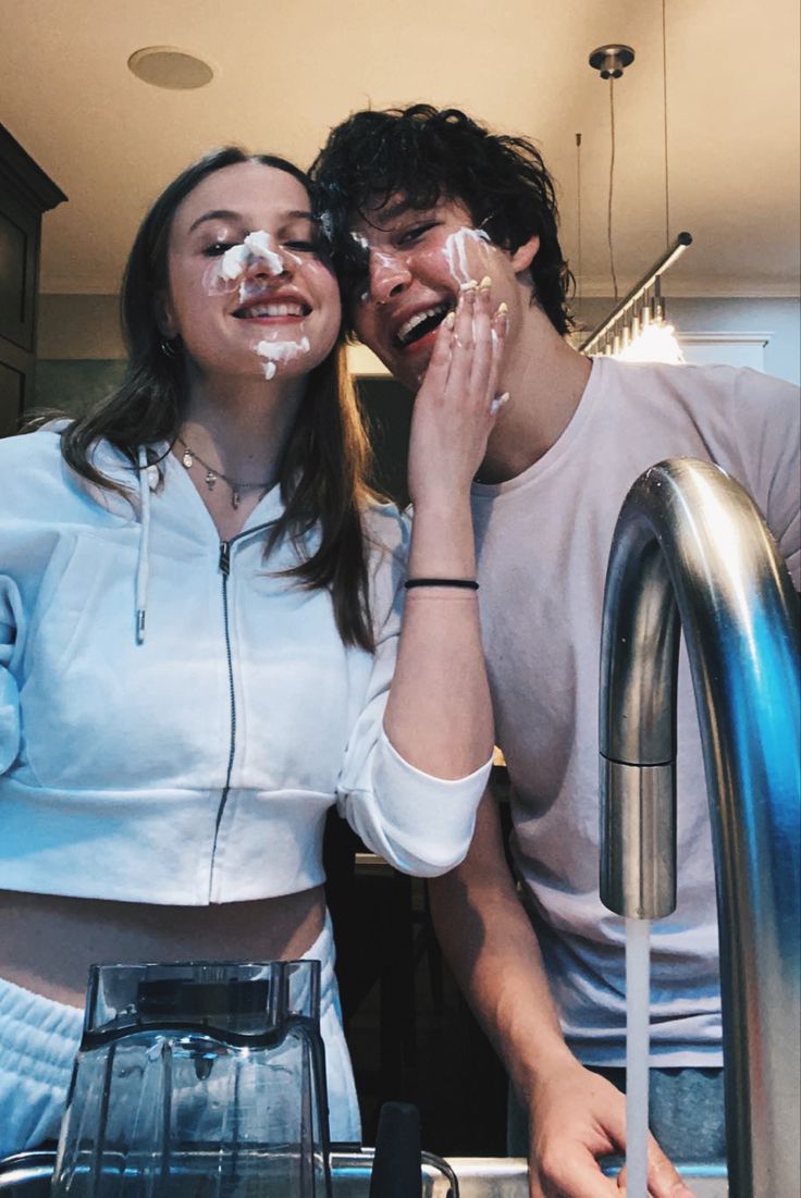 a man and woman standing next to each other in front of a counter with food on it