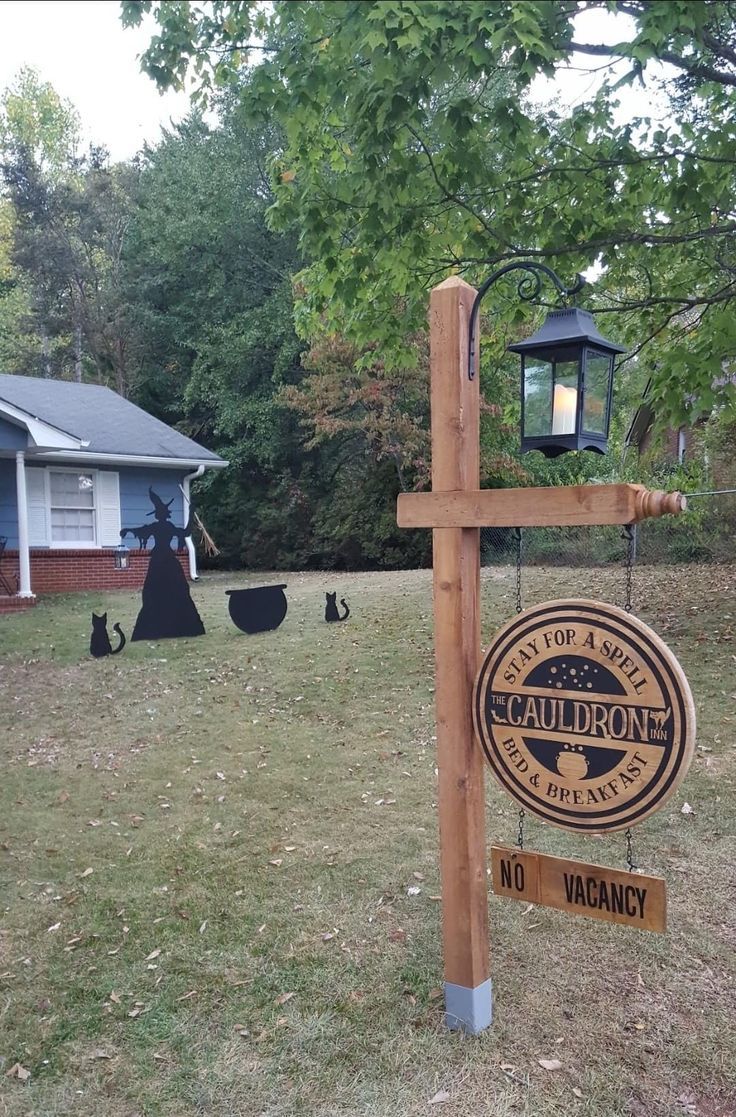 a wooden cross with a sign hanging from it's side in front of a house