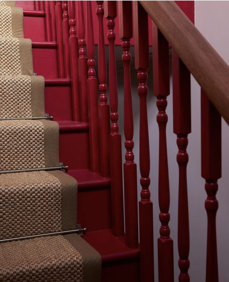 red carpeted stairs with beige carpeting and wooden handrails in residential home