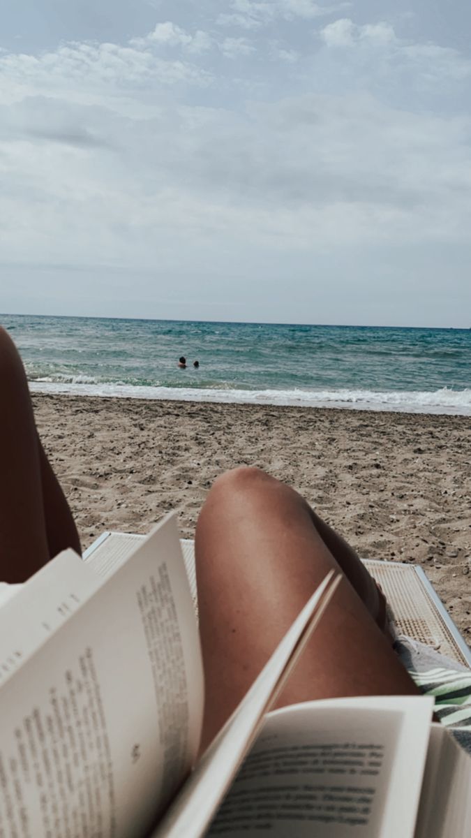 a person reading a book on the beach