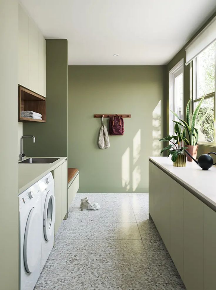 a washer and dryer sitting in a room next to a window with potted plants