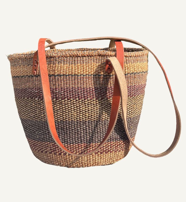 The Sophia will be on our shoulder all summer long. We can't wait to carry this vintage inspired sisal bag to the beach and while shopping in town. The Sophia is a perfect everyday bag that is roomy enough for essentials and more. 11" high by 12" wide by 6" deep. 17.5" handle drop. Made by a wonderful group of women artisans in Kenya. No inside pocket. 100% Sisal Body. Leather Strap. Brown Beach Bag With Rolled Handles For Vacation, Casual Brown Beach Bag With Rolled Handles, Brown Straw Bag With Adjustable Strap For Market, Beige Basket Shoulder Bag With Rolled Handles, Brown Basket Beach Bag With Rolled Handles, Brown Bucket Bag With Long Handle For Travel, Natural Fiber Bucket Shoulder Bag For Market, Brown Natural Fiber Bucket Bag For Everyday Use, Brown Handwoven Basket-shaped Bucket Bag