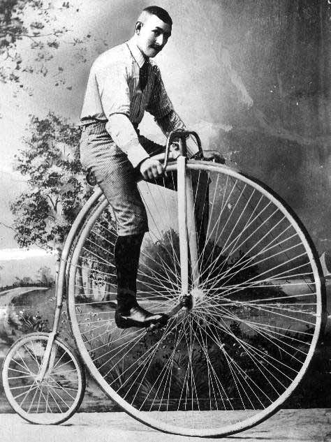 an old time photo of a man standing on top of a penny - wheel bicycle