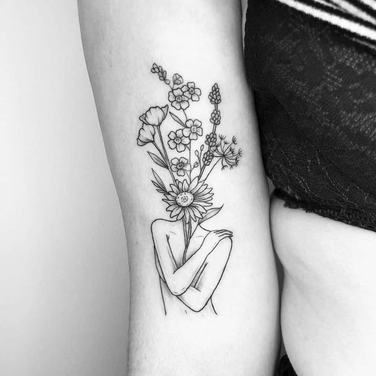 a black and white photo of two women with tattoos on their arms, one holding a bouquet of flowers