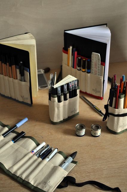 an assortment of pens and pencils sitting on top of a table next to a book