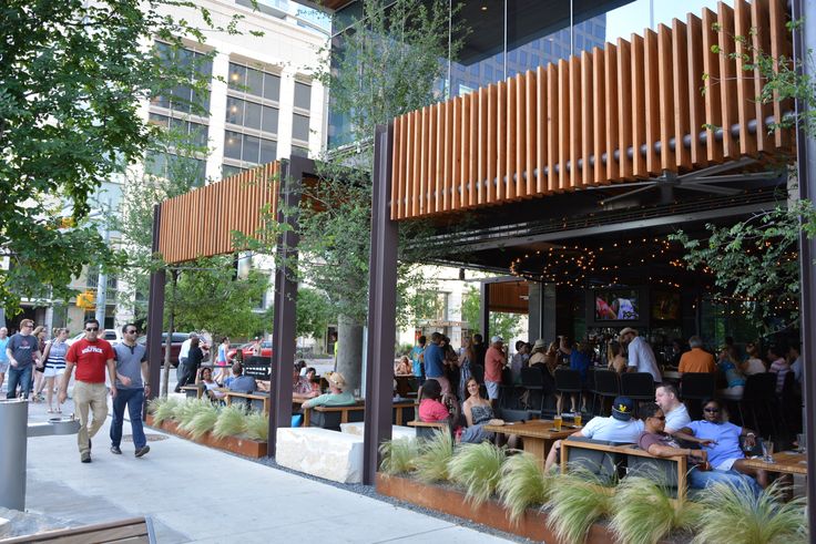 many people are sitting at tables outside on the sidewalk