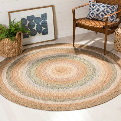 a round rug in the corner of a room next to a chair and potted plant