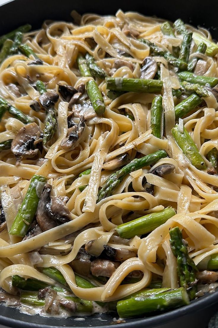 a skillet filled with pasta and asparagus