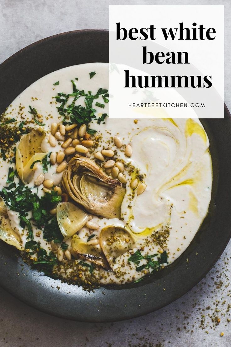 white bean hummus in a black bowl, with artichokes, pine nuts, parsley. White Bean Hummus, Vegan Appetizer, Bean Hummus, Searing Meat, 64 Impala, Gluten Free Appetizers, Vegan Snack, Cooking With Olive Oil, Hummus Recipe