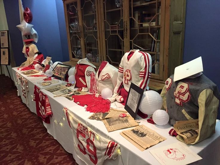 the table is covered with red and white football jerseys, paper mache sculptures, and other memorabilia