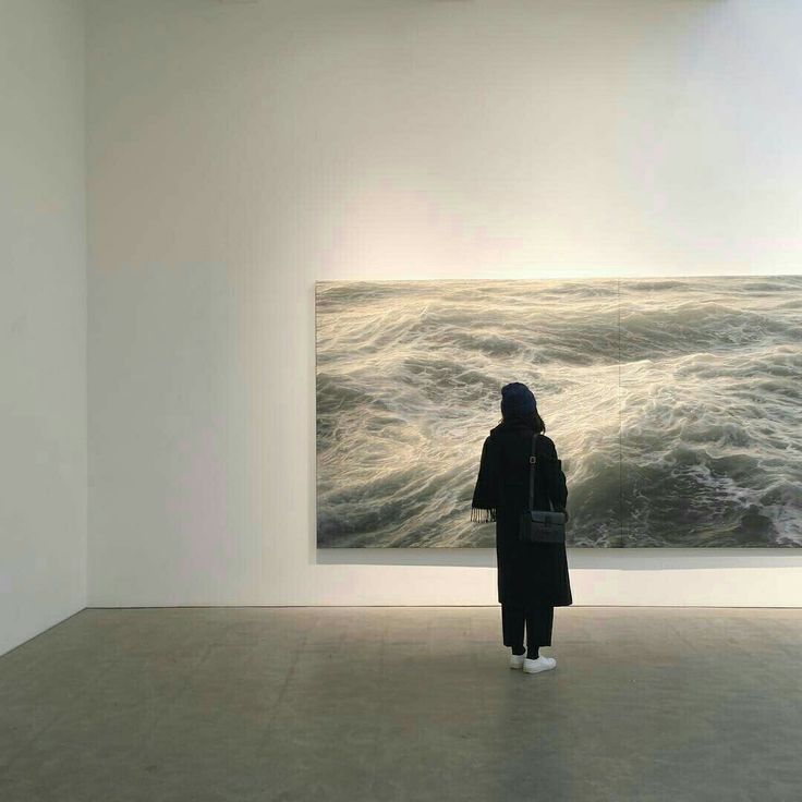 a person standing in an art gallery looking at a painting on the wall and water