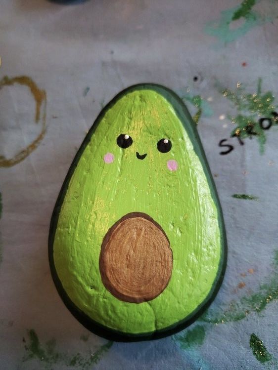 an avocado painted with acrylic paint sitting on top of a table