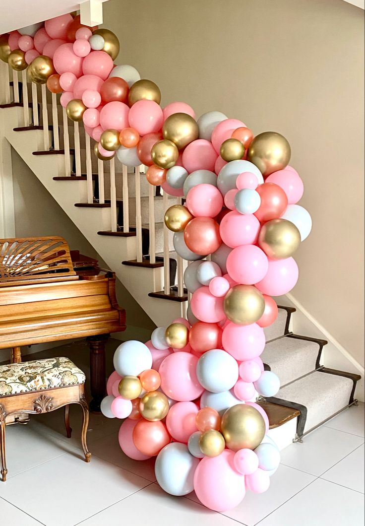 the staircase is decorated with pink, gold and white balloons as well as a grand piano