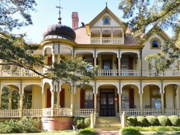 a large yellow house sitting in the middle of a lush green forest filled with trees