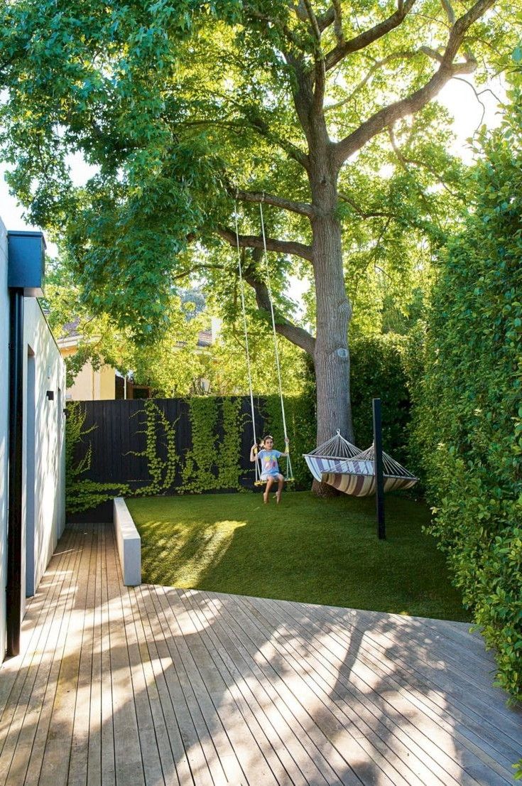 a person sitting in a hammock on a deck next to a large tree