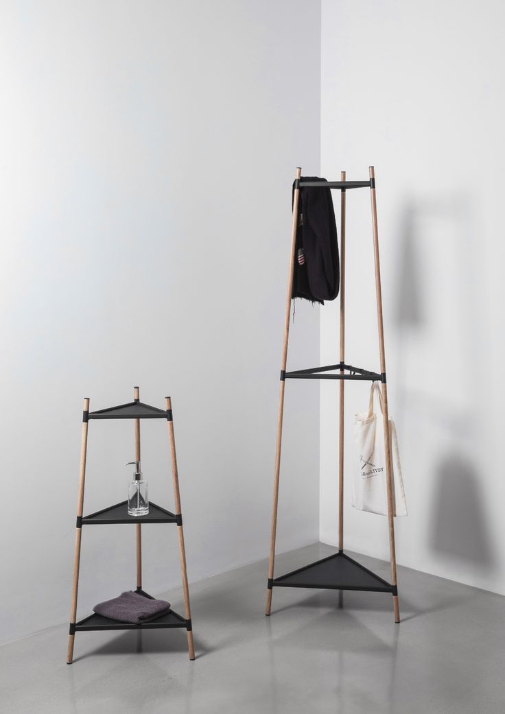 two shelves with clothes hanging on them in an empty room next to a white wall