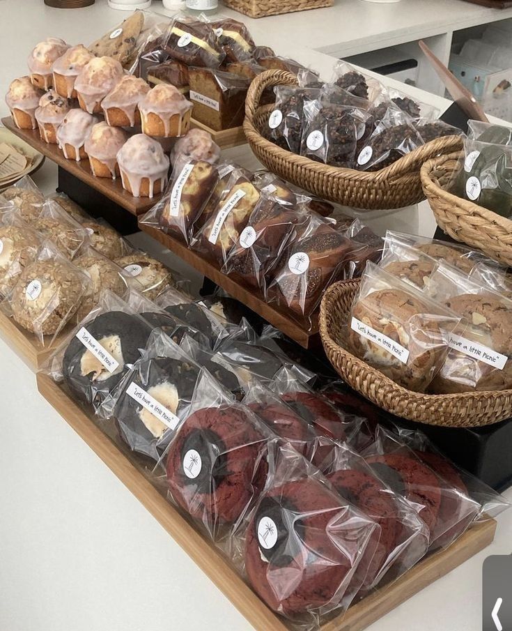 a display case filled with lots of different types of cakes and muffins in plastic bags