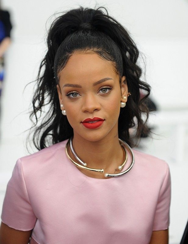 a close up of a person wearing a pink shirt and necklace with pearls on it