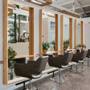 a row of chairs sitting next to each other in front of a wall with mirrors on it