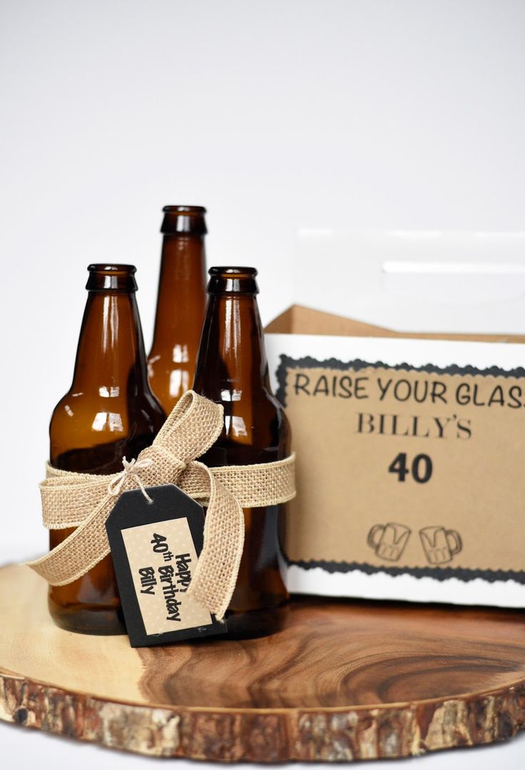 three brown beer bottles sitting on top of a wooden table next to a sign that says raise your glass billy's 40