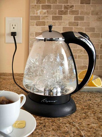 a glass tea kettle sitting on top of a counter next to a cup of coffee