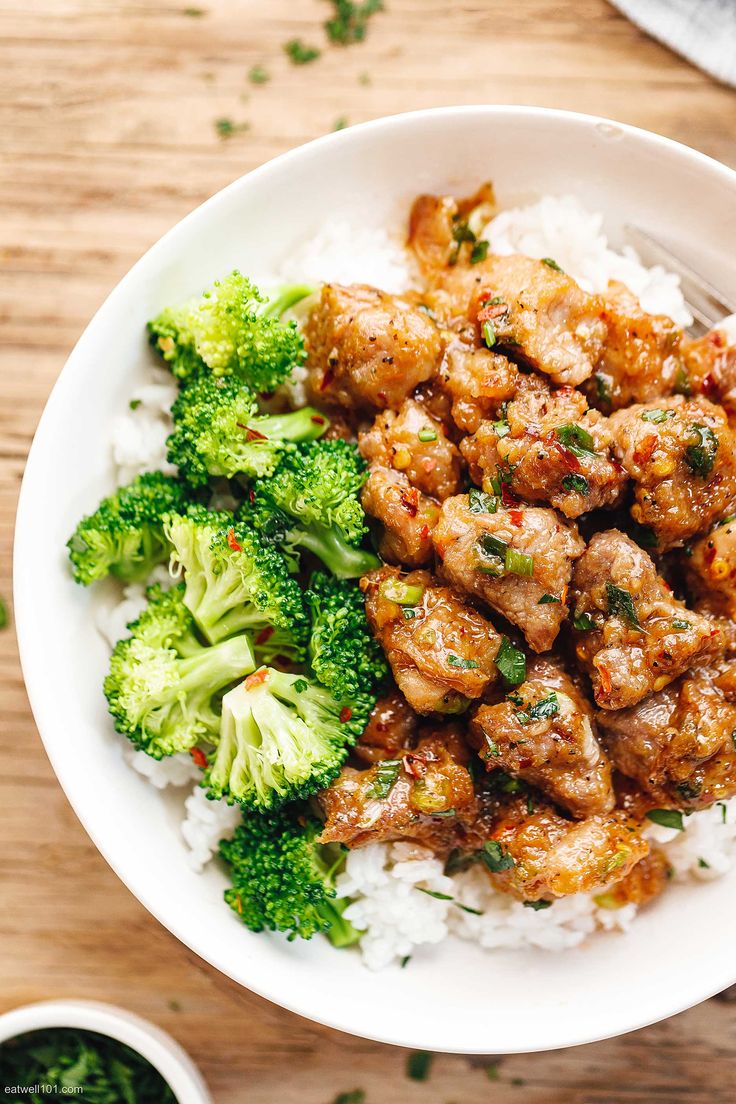 a white bowl filled with meat and broccoli on top of rice next to sauce