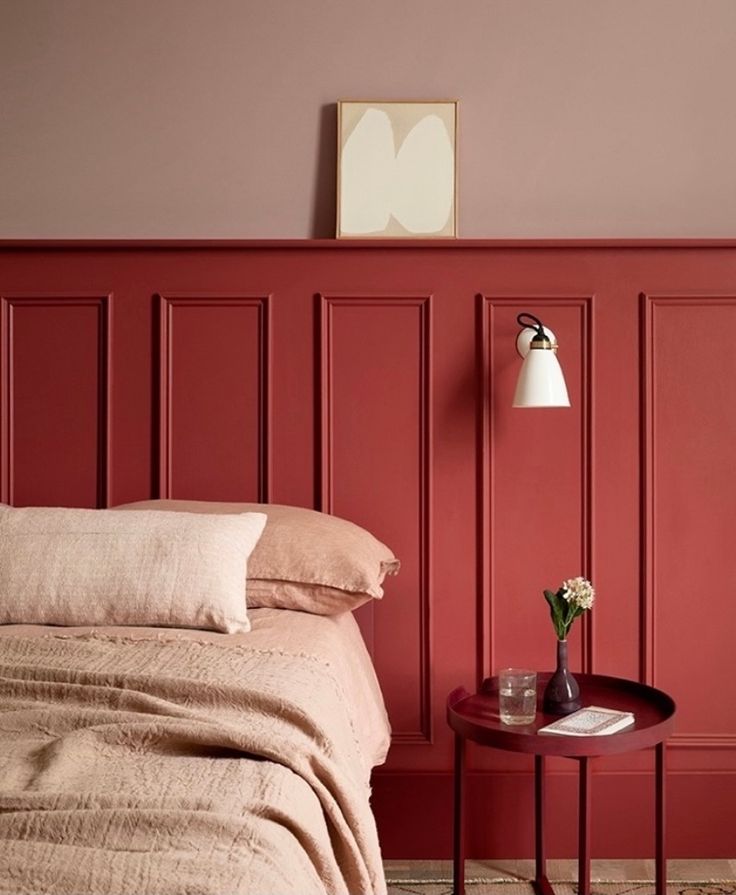 a bed room with a neatly made bed and red walls