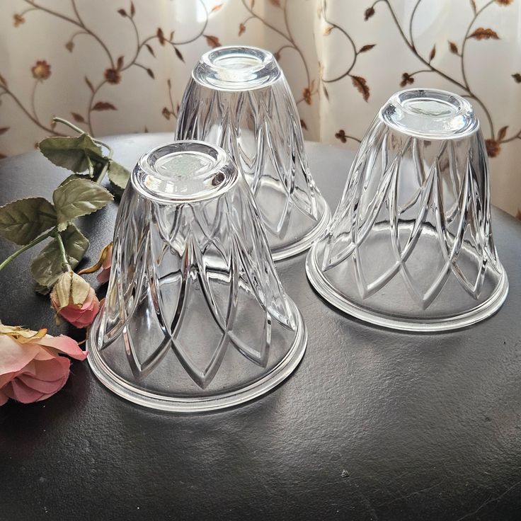 two glass candlesticks sitting on top of a table next to a flower vase