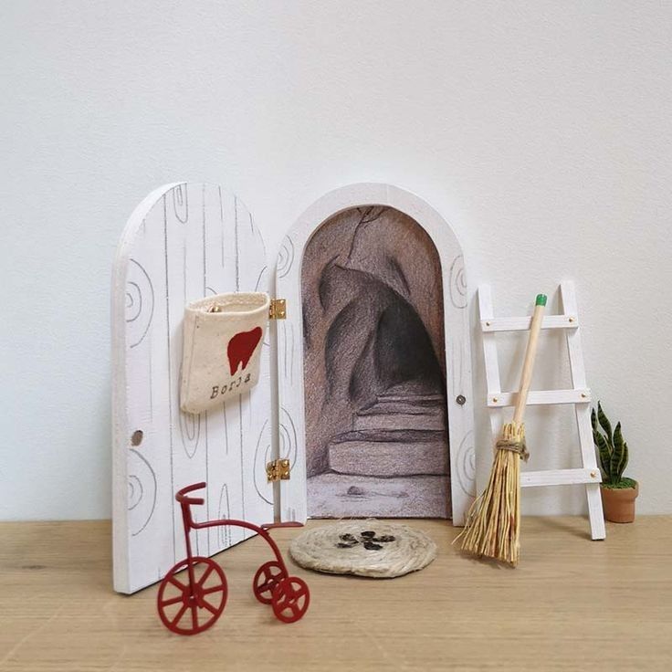 there is a miniature house with a cat in the door and a broom next to it