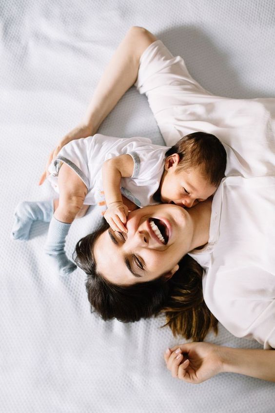 a woman laying on top of a bed holding a baby