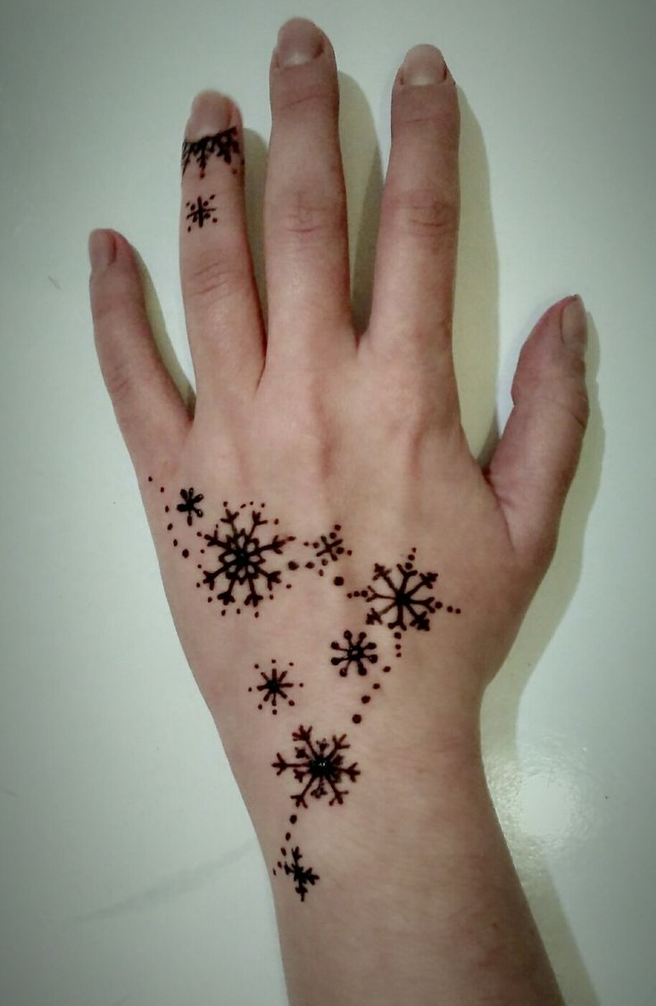 a person's hand with black ink on it and snowflakes all over the palm