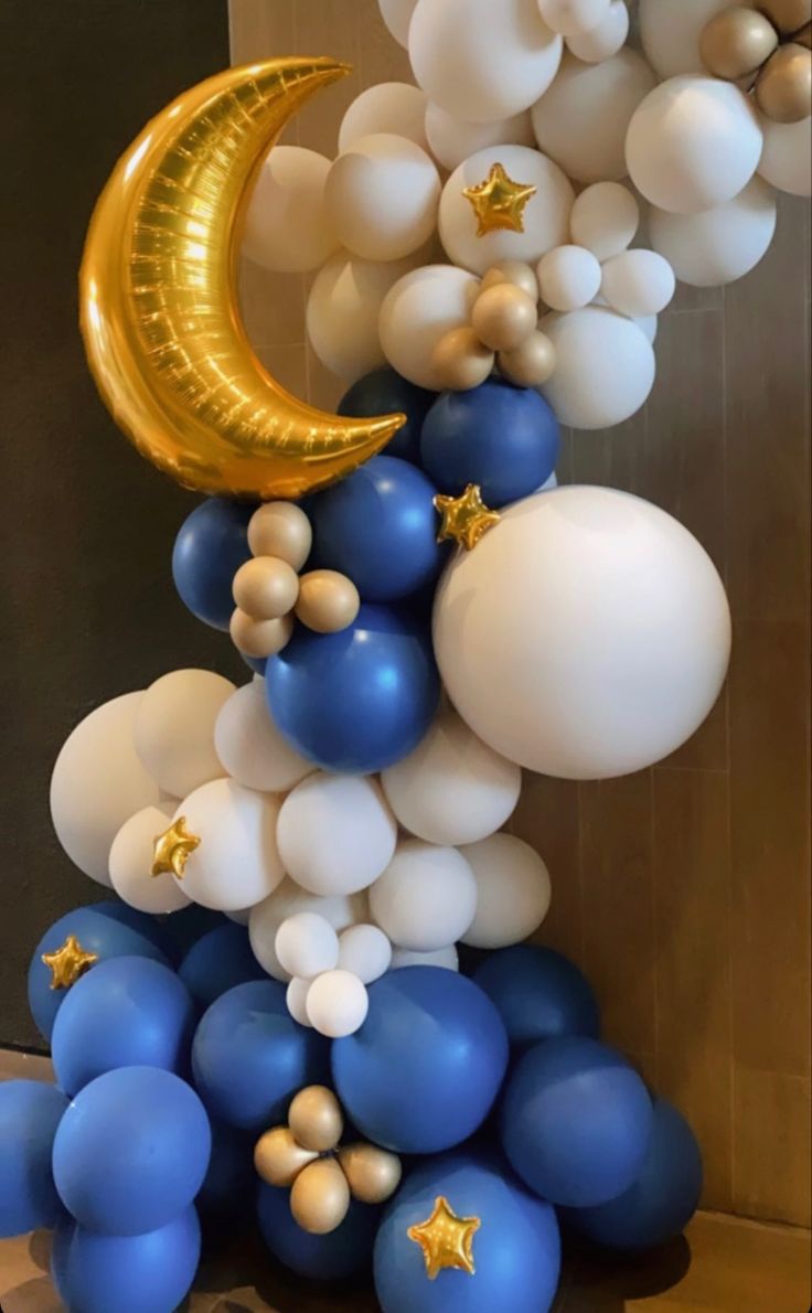 balloons and stars are arranged in the shape of a moon on top of a pile of blue and white balloons