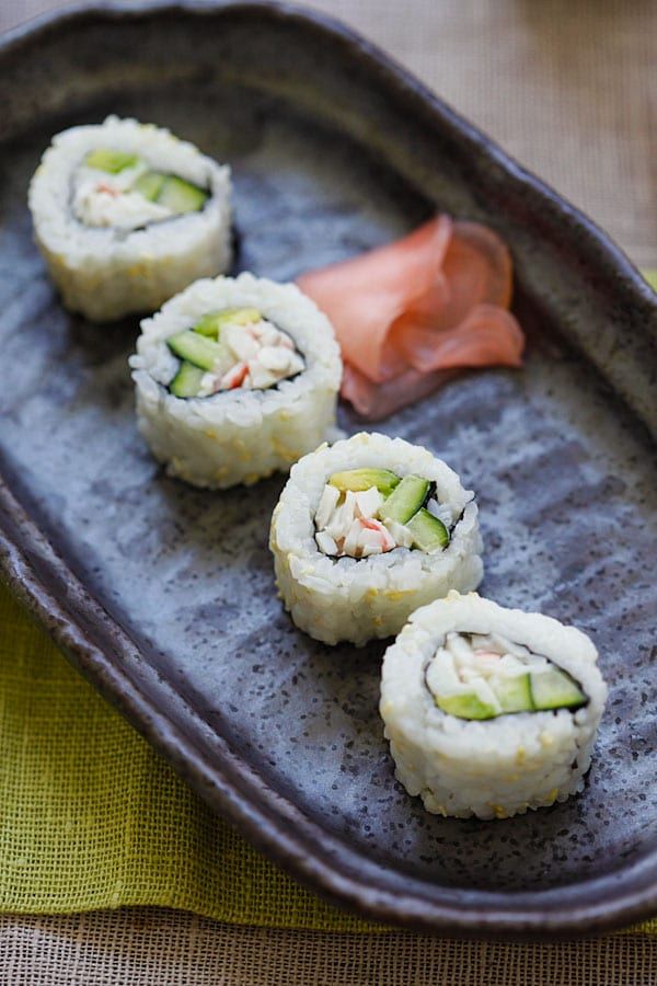 sushi rolls with cucumber and salmon are on a gray plate next to a green napkin