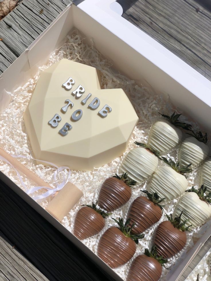 a box filled with chocolate covered strawberries on top of a wooden table next to other items