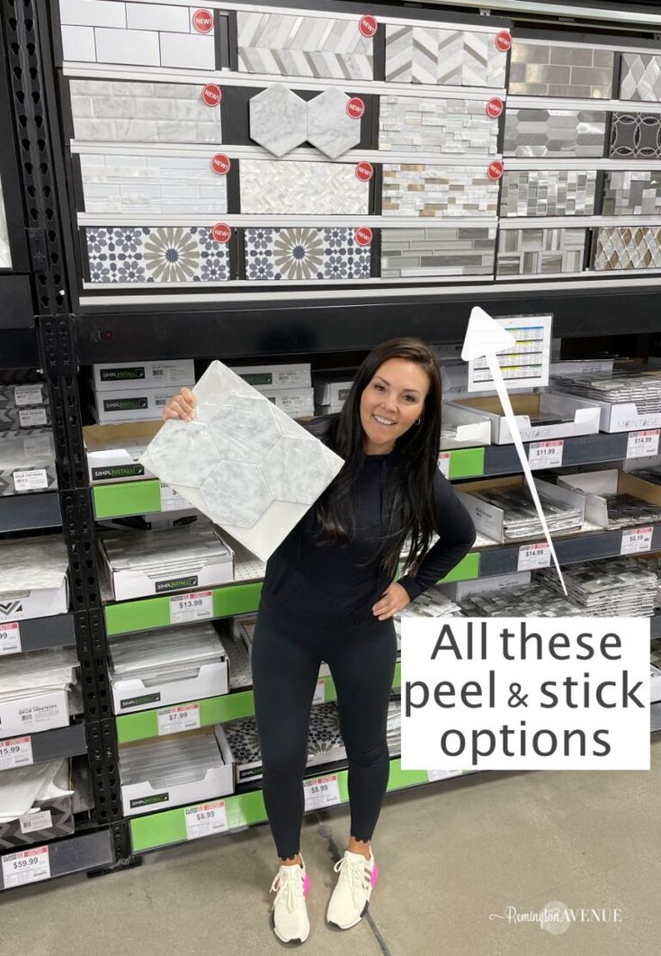 a woman standing in front of stacks of boxes holding up a sign that says all these peel and stick options