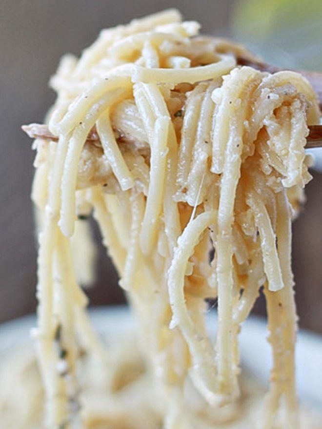 a close up of a spoon full of food with pasta on it's fork