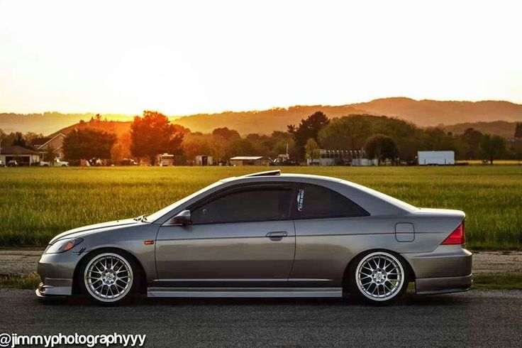 a silver car parked on the side of a road in front of a green field