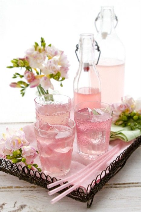 two pink drinks are sitting on a tray