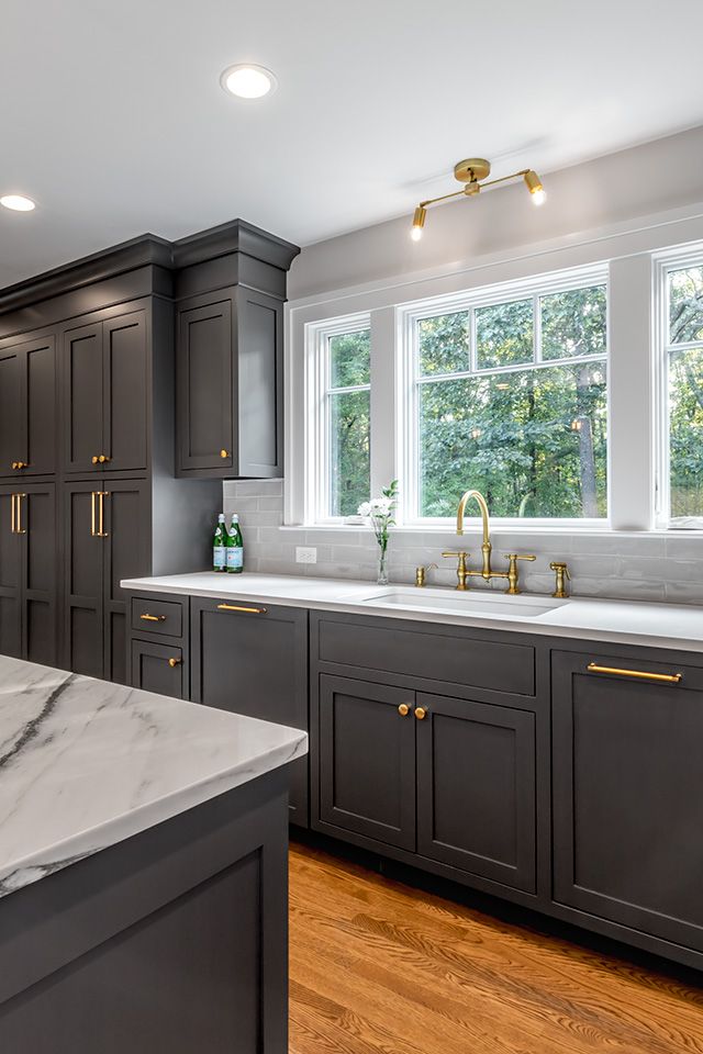 a large kitchen with marble counter tops and dark cabinets, along with hardwood floorsing