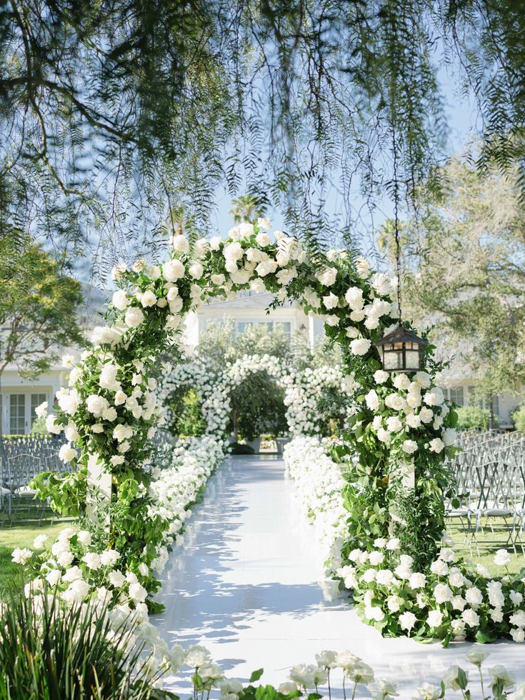 an outdoor ceremony with white flowers and greenery