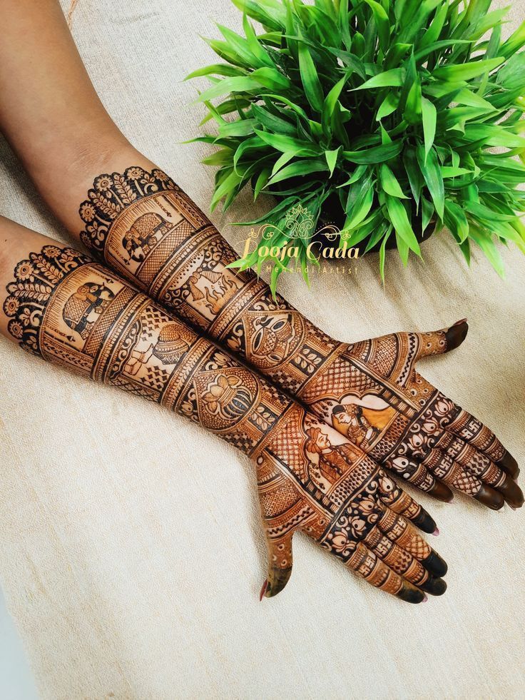 two hands with hendi designs on them next to a potted plant