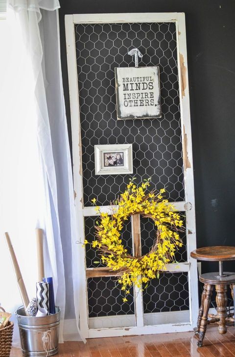 a door with a wreath on it in front of a black wall and wooden floor