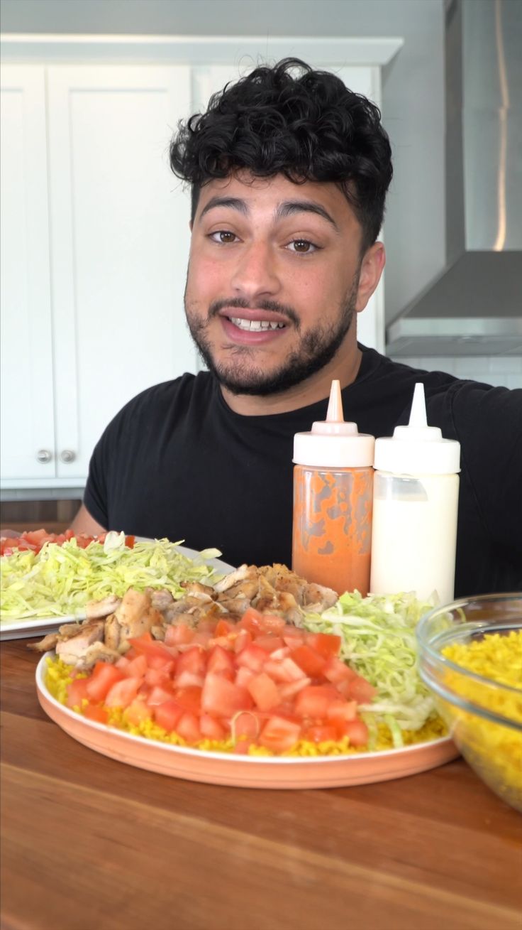 a man sitting at a table with a plate of food and condiments in front of him