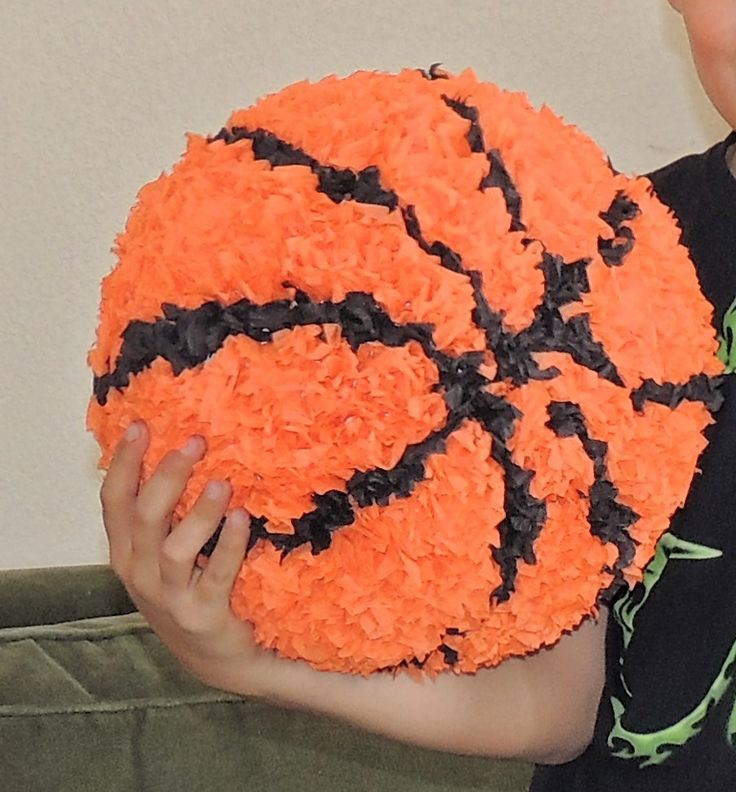 a young boy holding a basketball cake in his hands