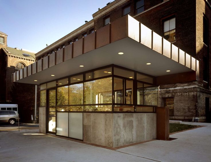 an empty building with lots of windows on the front and side of it, next to a white van