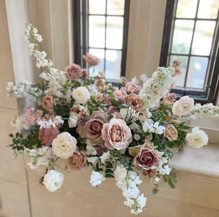 an arrangement of flowers in front of two windows