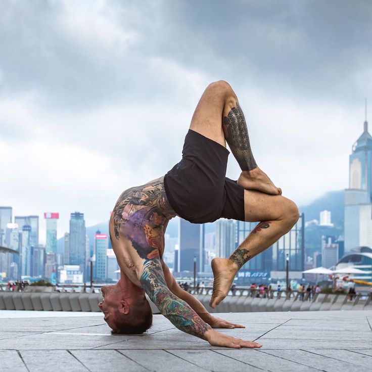 a man doing a handstand on the ground in front of a cityscape