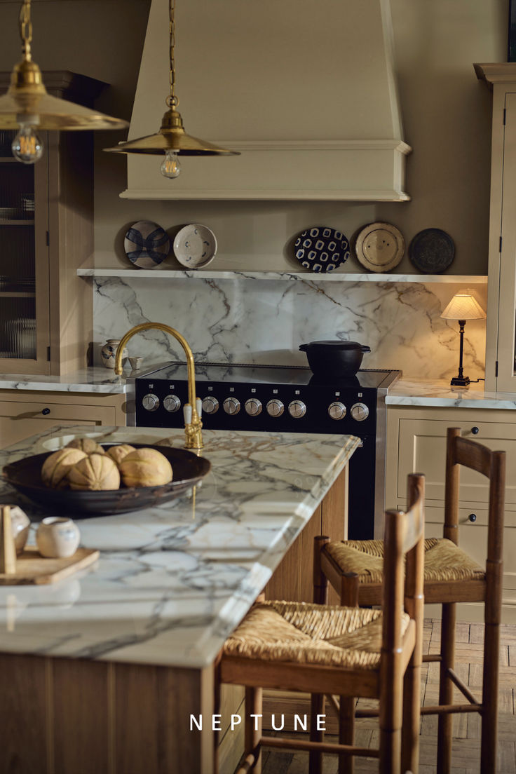 a kitchen with marble counter tops and wooden chairs in front of an island that has two plates on it