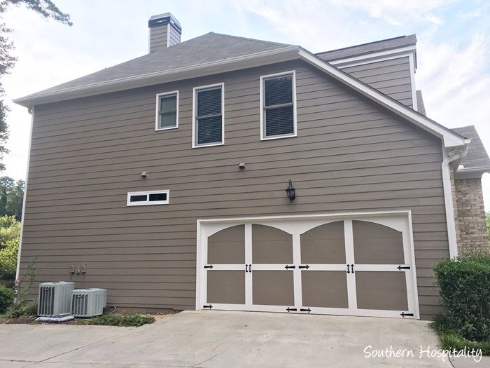 a two car garage with an air conditioner in front of it and a window on the second floor