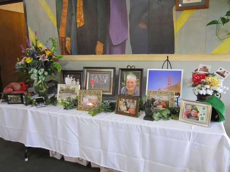 a table topped with pictures and flowers on top of a white tablecloth covered table